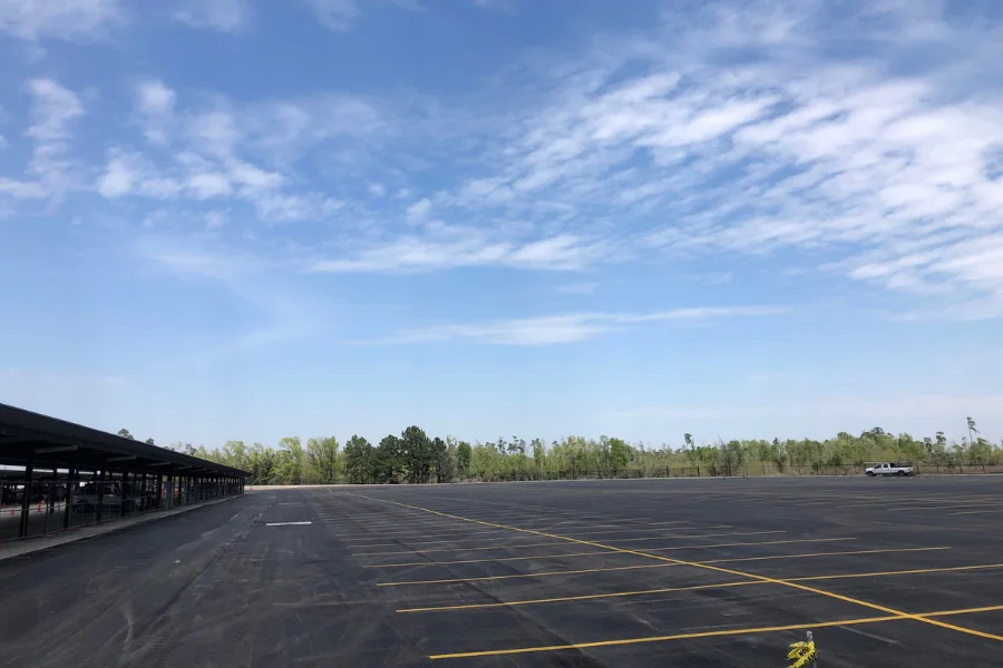 Completed commercial parking lot paving and striping project with newly installed asphalt and marked parking spaces.